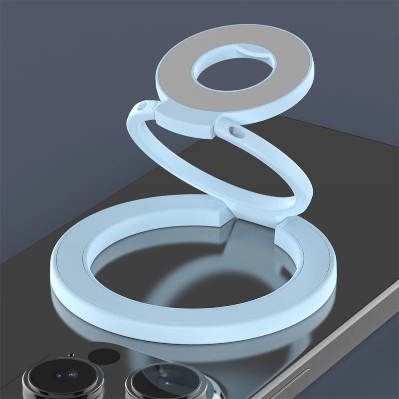 A white magnetic ring grip with a foldable kickstand shown on a dark surface.