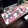 Pink and gray abstract wave pattern mouse pad placed on a wooden desk next to a computer monitor.