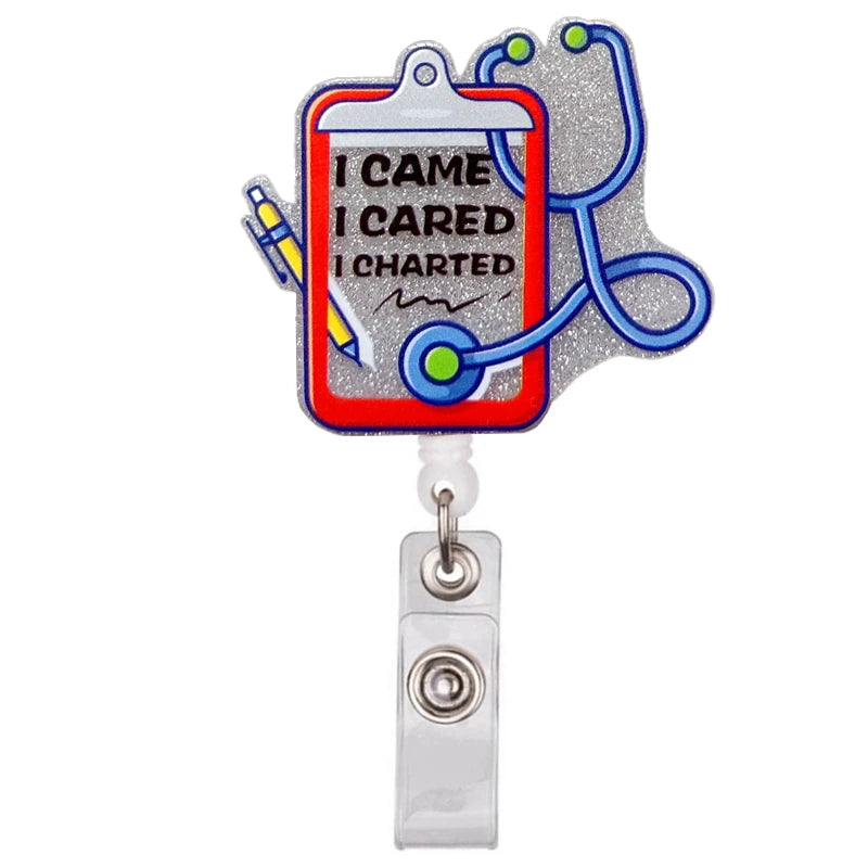 A silver badge reel holder featuring a cartoon medical theme with text I CAME I CARED I CHARTED and a stethoscope.