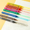 A collection of colorful wax crayons arranged diagonally on a white sheet of paper.