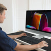 A man uses an extra large anti-slip rubber mouse pad on a desktop computer.