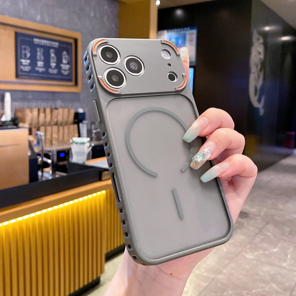 A hand holds a gray frosted magnetic silicone case for an iPhone, displaying the back design.