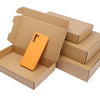 An orange smartphone is placed inside a brown kraft gift box with other boxes stacked behind it.