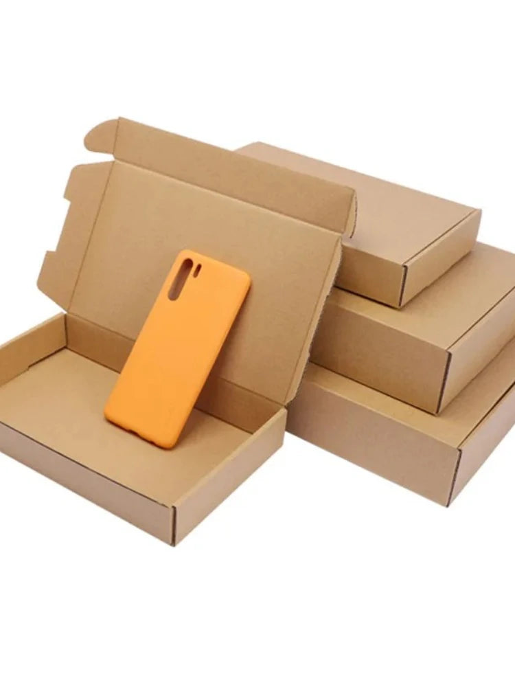 An orange smartphone is placed inside a brown kraft gift box with other boxes stacked behind it.