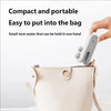 A hand holds a small, white handheld heat sealer device next to a light beige purse.