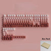A box pack of PBT double-shot cherry profile keycaps for mechanical keyboards arranged on a pink surface.