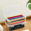 Clear storage box with lid containing colored pencils, crayons, and other art supplies.