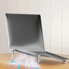 A silver foldable aluminum laptop stand is shown resting on a wooden surface, demonstrating its non-slip grip.