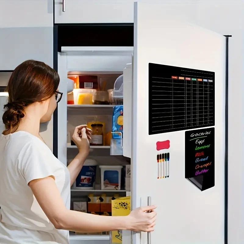 A woman looks into a refrigerator with a magnetic planning calendar set displayed on the door.