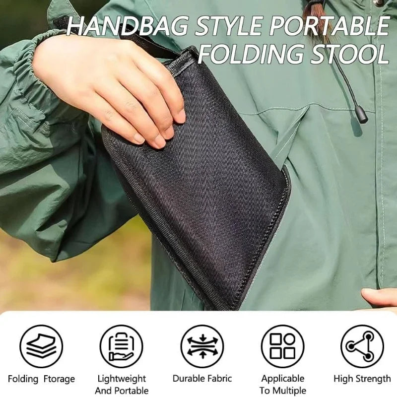 Una mano sostiene un taburete plegable negro diseñado para uso portátil al aire libre.
