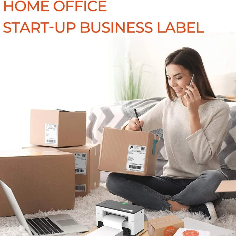 A woman is using a phone while sitting on a couch with several cardboard boxes and a laptop in the background.