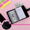 A pink background shows an A6 budget planner with a leather cover, a stack of cash, and a pen.