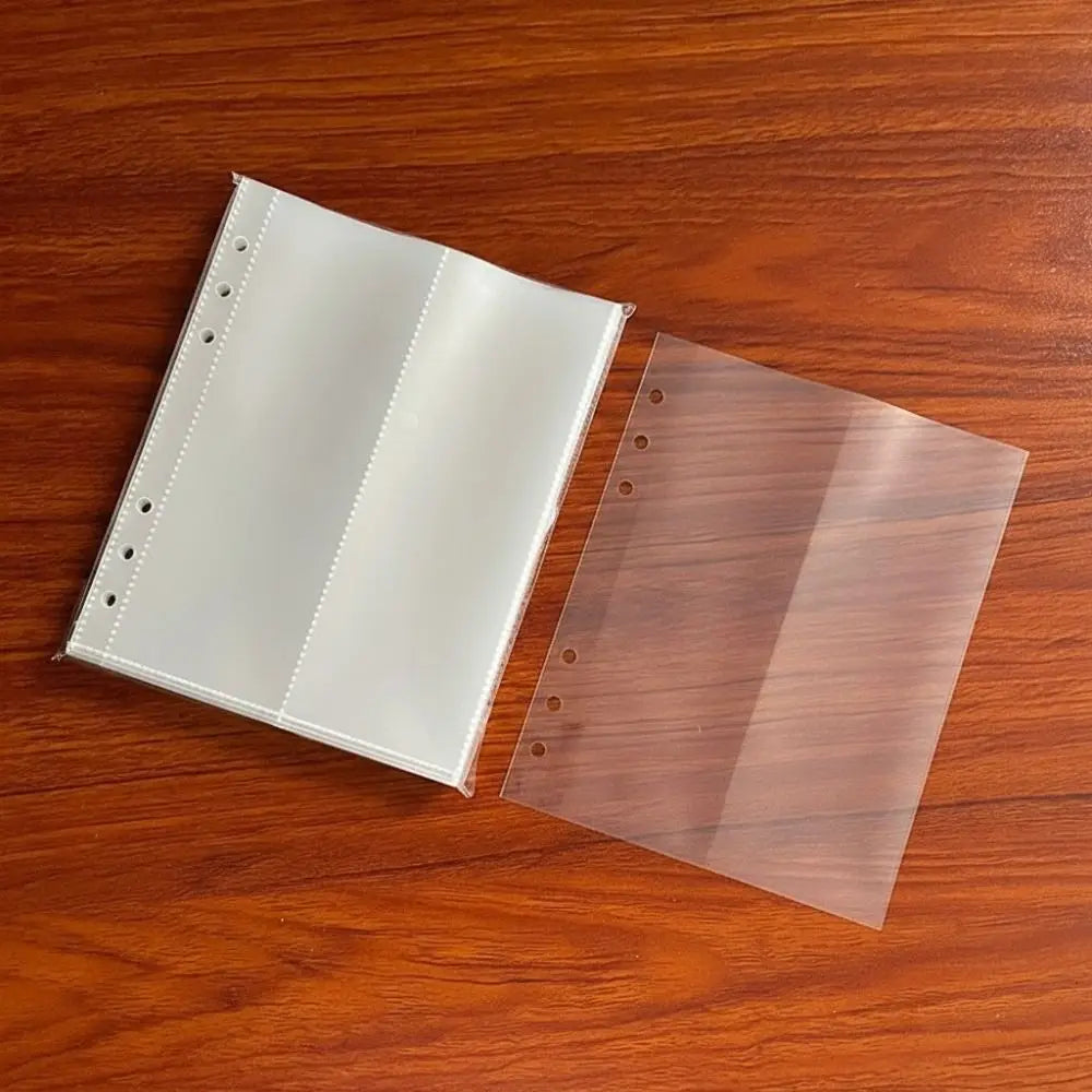 A transparent photo card binder sleeve with a white cover and a brown tinted plastic sheet resting on a wooden surface.