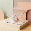 A clear acrylic stand for a tablet or phone with pink adjustable arms, set against a soft pink and green background.