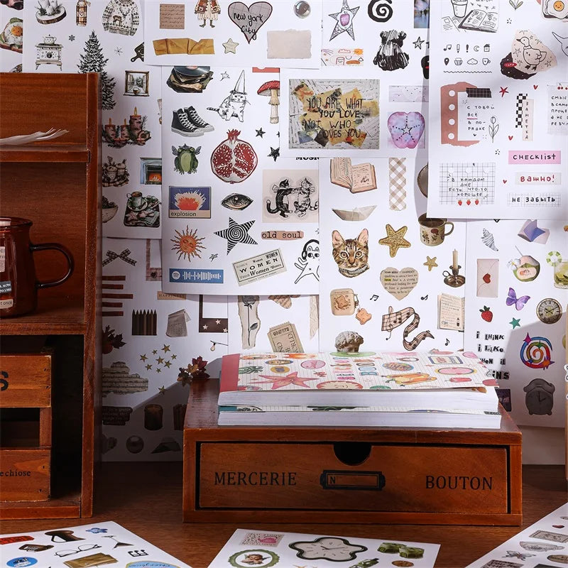 Aesthetic scrapbooking sticker book featuring nature and animal patterns displayed next to a wooden storage box.