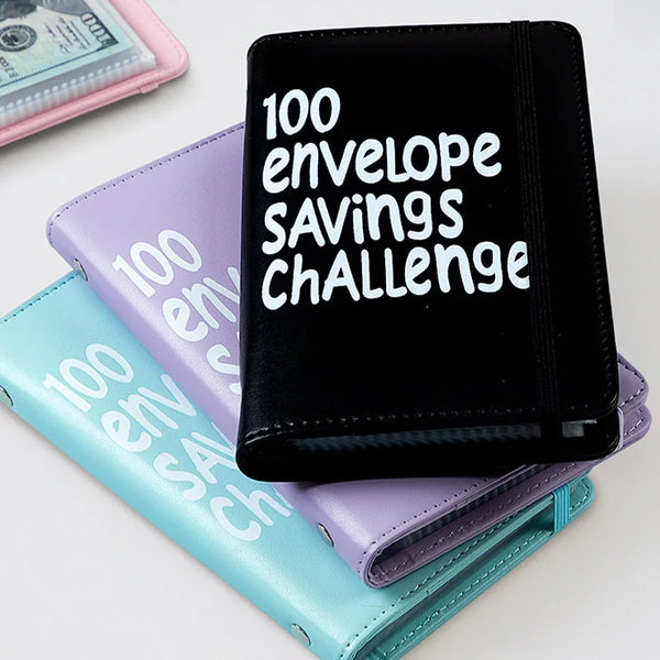A black budget planner with leather envelopes labeled 100 envelope savings challenge is shown next to a purple and teal plann