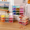 Clear acrylic storage boxes filled with various colored beads and stones for jewelry making or crafting