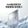 A silver GaN fast charger is shown resting on a snowy surface.