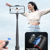 A woman is using a magnetic remote control attached to a selfie stick to take a photo.