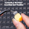 A hand is using a pair of tweezers to tear off a yellow adhesive fixer pad from a black tool.