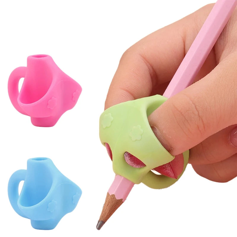 A hand holds a pink silicone pencil grip writing corrector, showing the grip and the pencil tip.