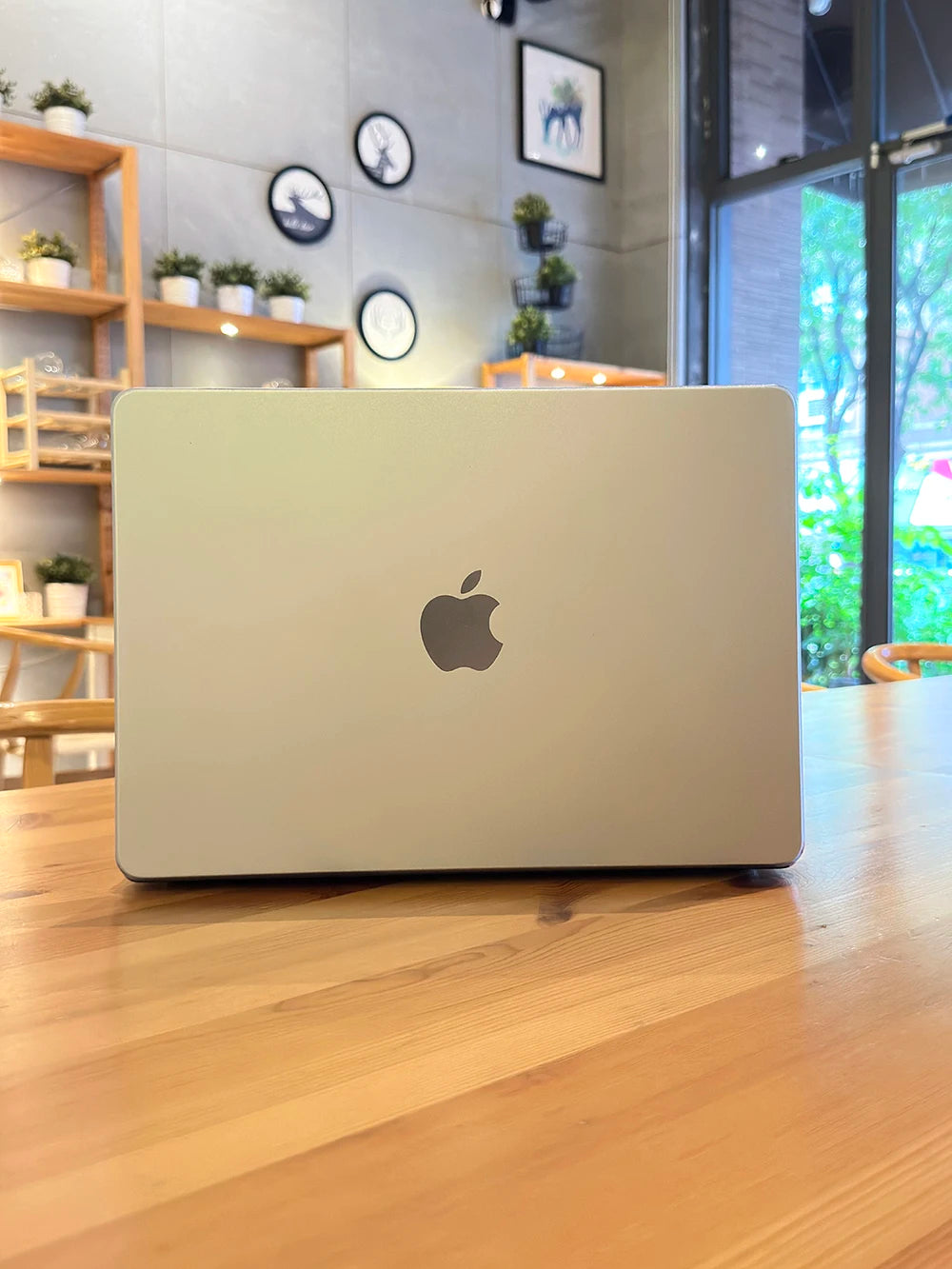 Ein silberner Laptop liegt auf einem Holztisch in einer hellen Innenumgebung.