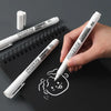 A hand holds a white permanent marker and a white cap against a black spiral notebook.
