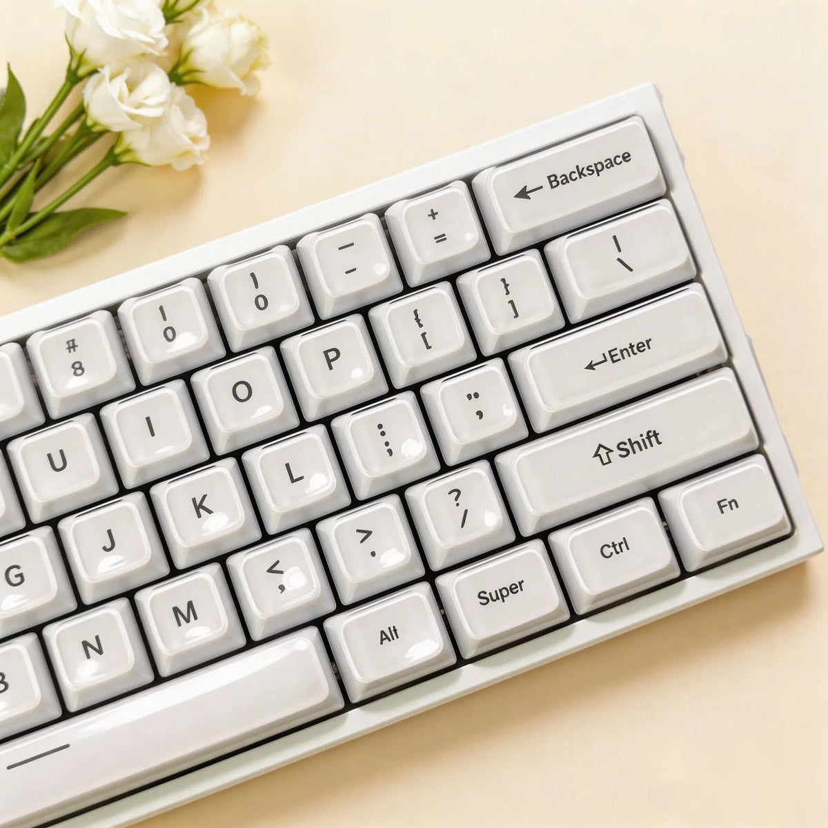 A close-up view of a white mechanical keyboard with light-colored keycaps and a sprig of white flowers.