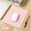 A pink portable gaming mouse pad with a white wireless mouse and a black stylus resting on a wooden surface.