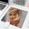 A mouse pad featuring a close-up image of a playful doll face with light hair and blue eyes.