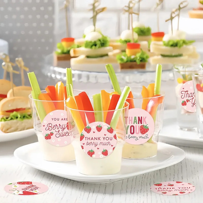 A display of strawberry thank you adhesive stickers in various shades and designs on a white plate.