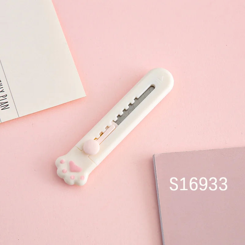 A white portable pet claw tool knife with a pink heart detail is shown on a light pink background.