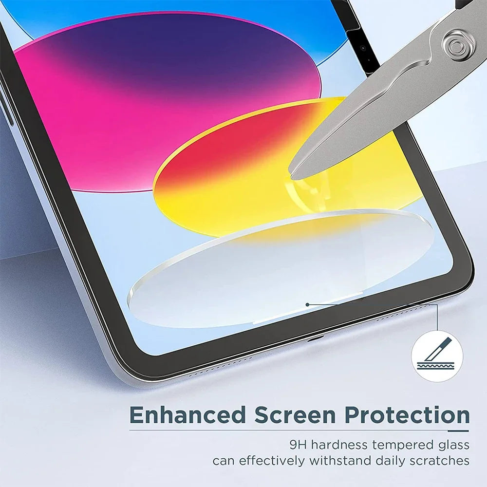 A close-up of an iPad screen showing colorful graphics and a glass protector being applied with a metal tool.