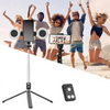 A selfie stick tripod is being used by people outdoors on a beach, showing the stick and a separate light unit.