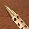 Close-up view of a brass bolt-action ballpoint pen with a textured barrel and silver tip.