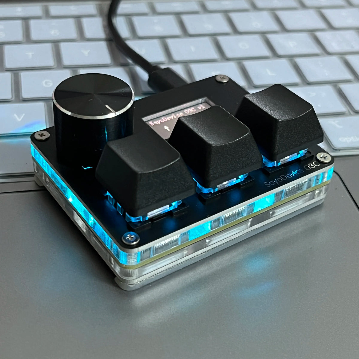 A close-up of a SayoDevice USB-C magnetic rapid trigger keyboard switch module resting on a gray laptop keyboard.