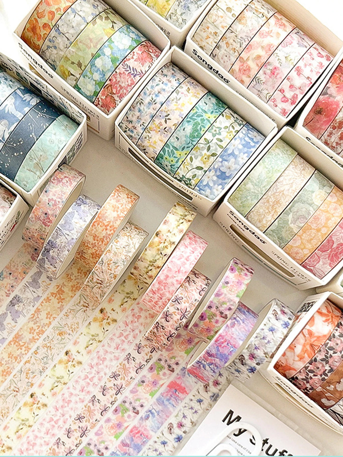 A collection of five rolls of floral washi tape in various pastel colors and patterns for journaling and crafts.