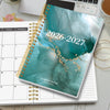 A spiral-bound academic planner showing the cover for 2026-2027 with a teal watercolor design and gold accents.