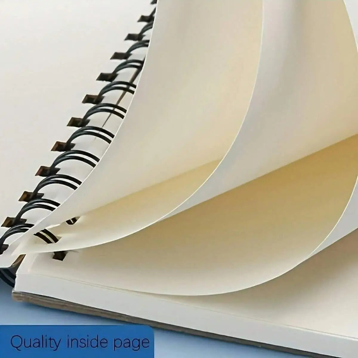 A close-up view of a spiral-bound sketchbook showing the quality inside page and thick watercolor paper.