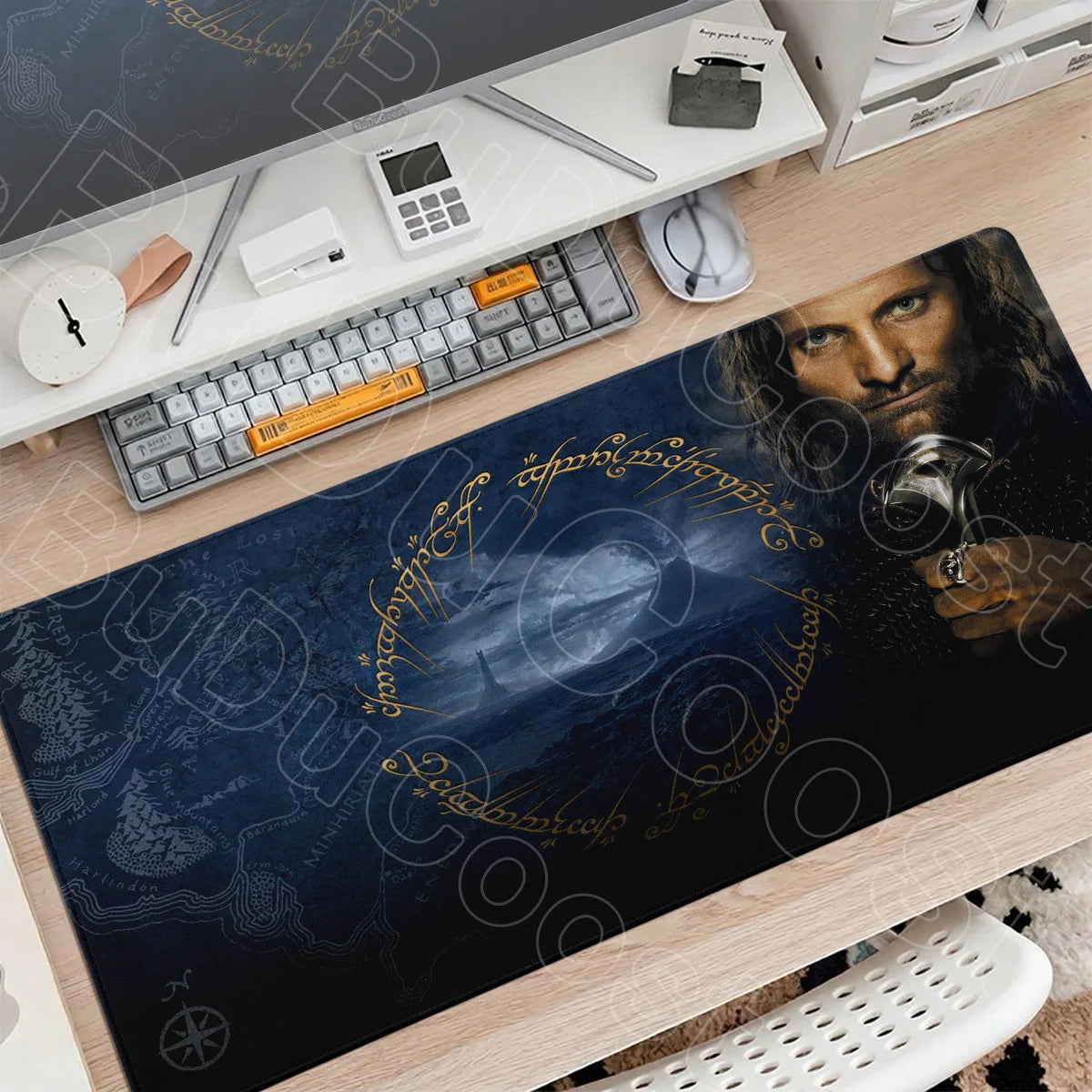 A large dark blue gaming mouse pad featuring Lord of the Rings imagery is displayed on a wooden desk with peripherals.