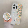 A hand holds a clear floral magnetic phone case for an iPhone featuring pink and yellow flowers.