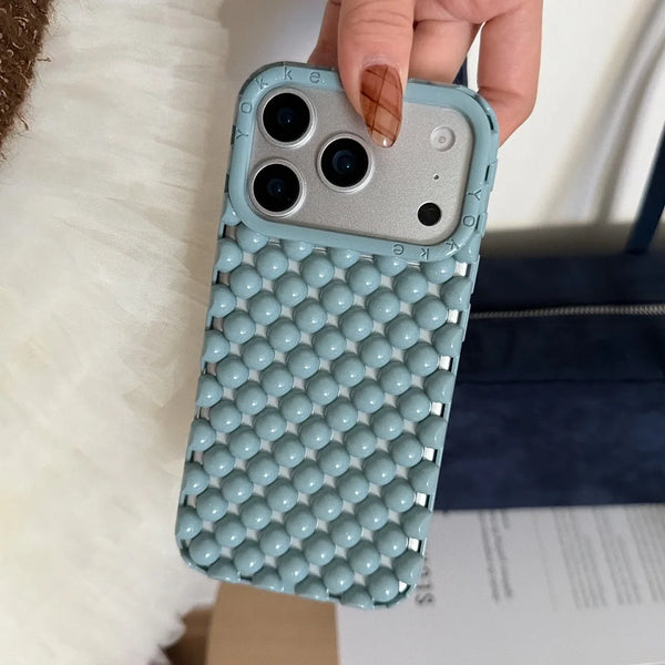A light blue 3D pearl hollowed phone case for an iPhone is held by a hand against a white background.