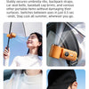 A portable handheld cooling fan in a matte orange color is shown being used to cool the neck area.