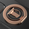A close-up of a rose gold MagSafe double-sided phone ring holder on a dark surface.