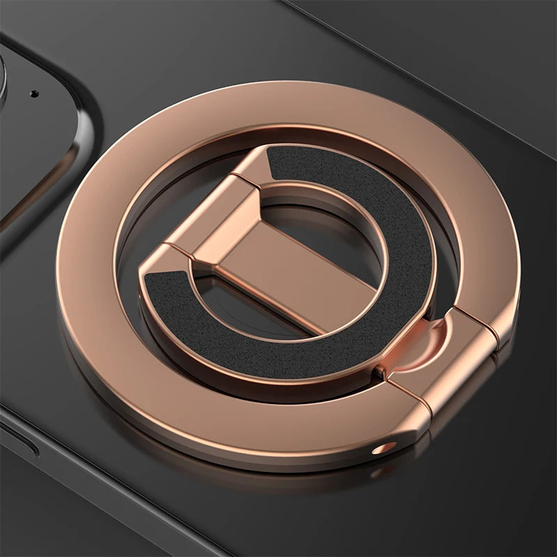 A close-up of a rose gold MagSafe double-sided phone ring holder on a dark surface.