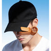 A close-up of a person wearing a black baseball cap and an orange portable rechargeable handheld cooling fan.