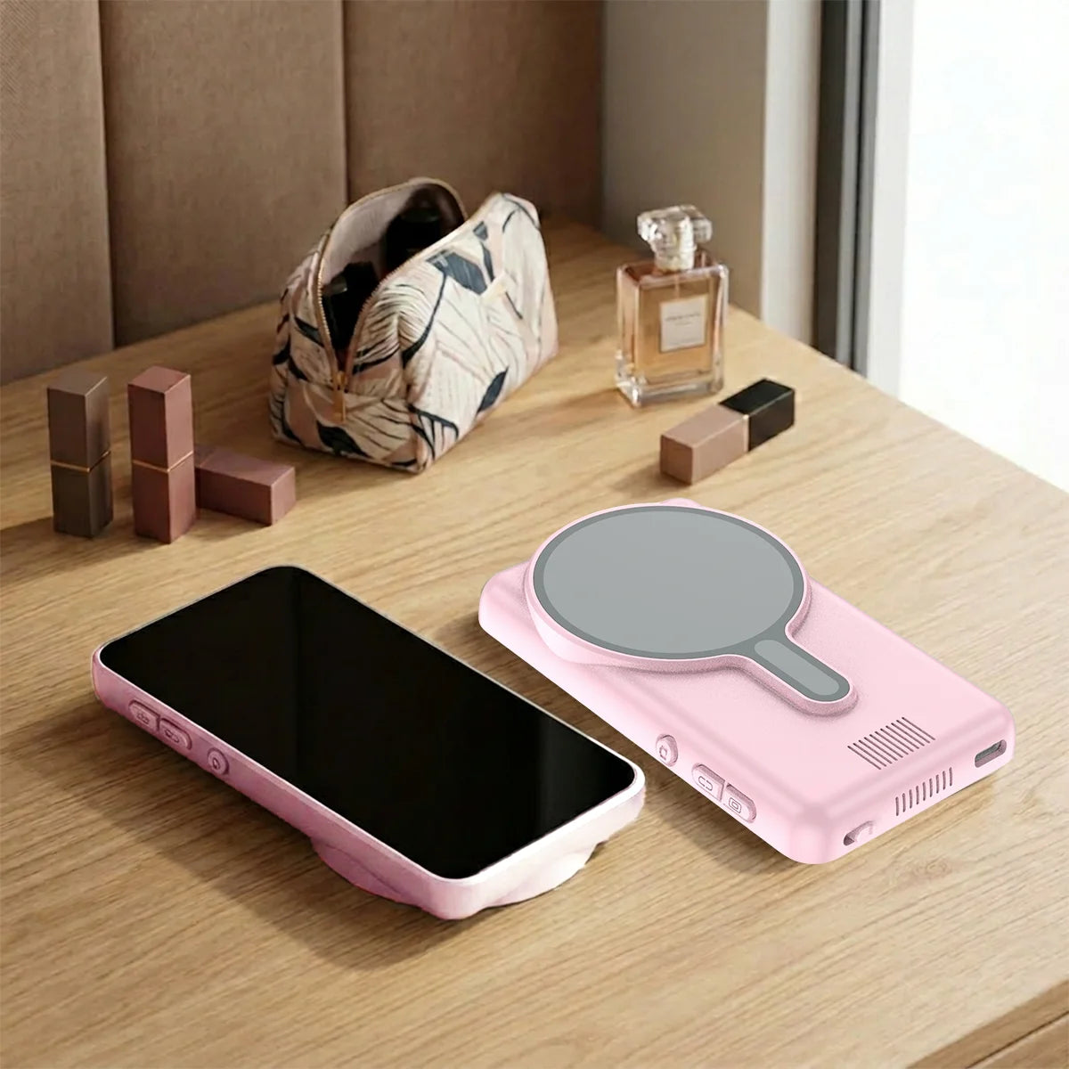 A pink magnetic selfie monitor screen is placed next to a black smartphone on a wooden table.