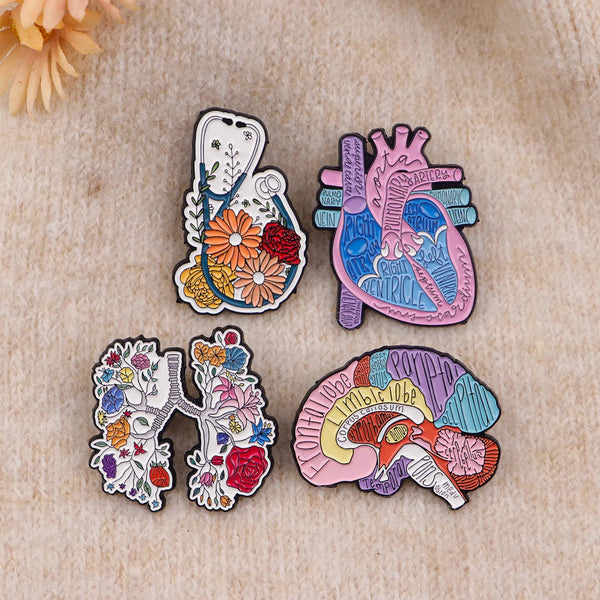 A set of enamel pins featuring medical themes including a heart, lungs, and brain.