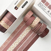 A set of red plaid and polka dot washi tape rolls displayed in a box for crafting and journaling.