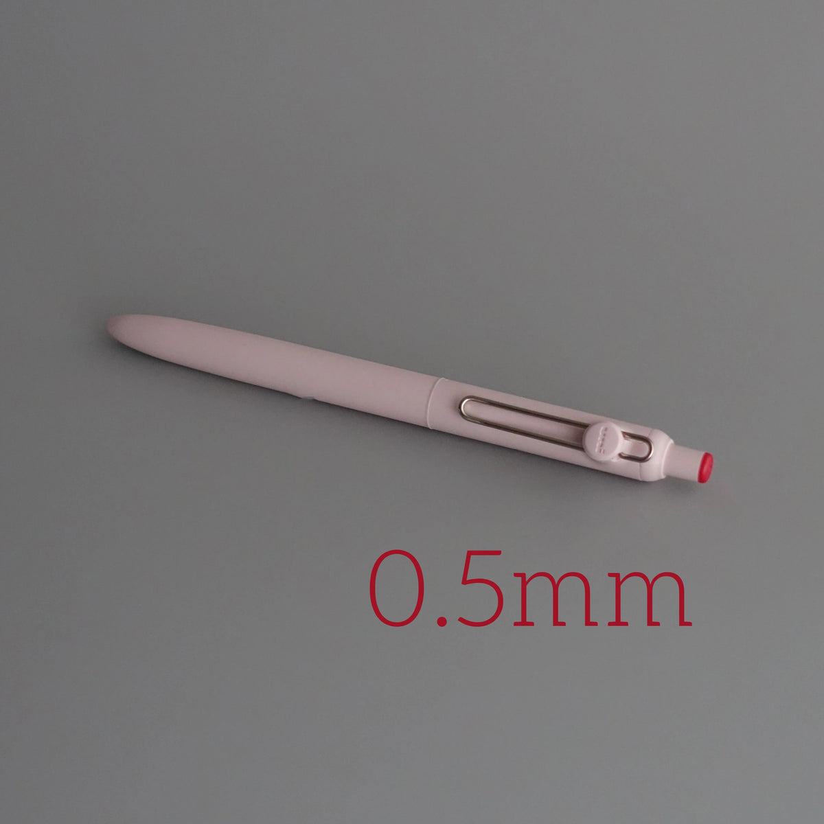 A close-up view of a light pink precision gel pen with quick-drying ink, showing its length and tip.